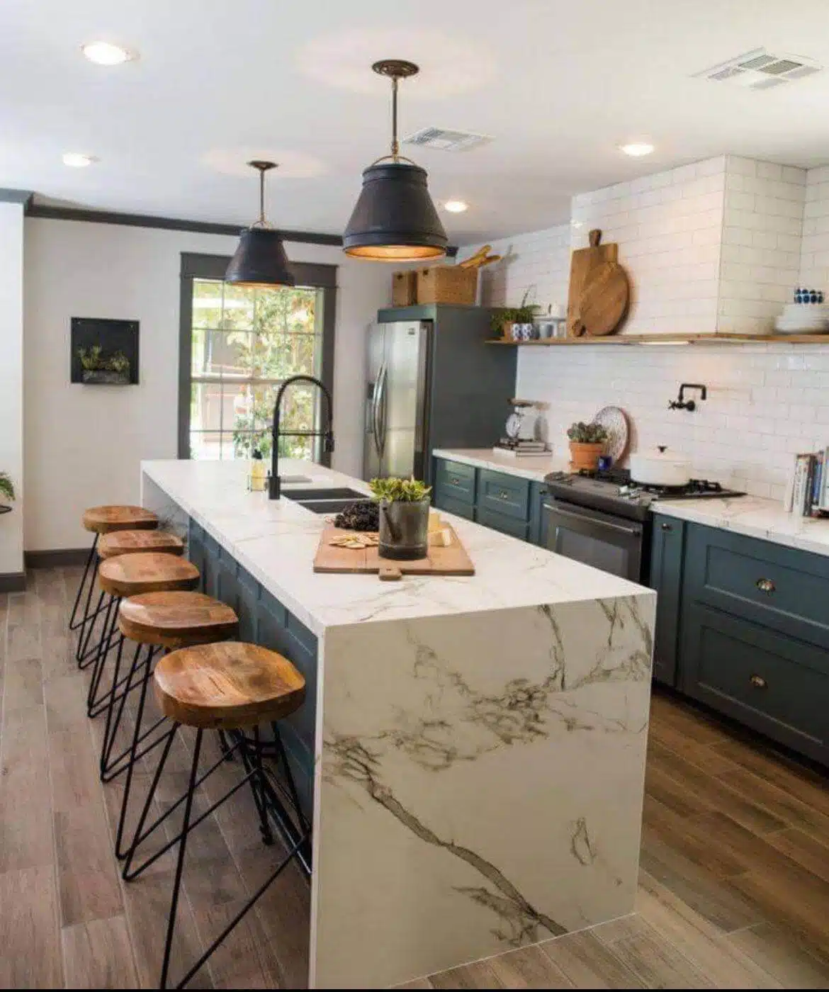 Kitchen with marble seated island and chairs, blue cabinets, and brown wood floors