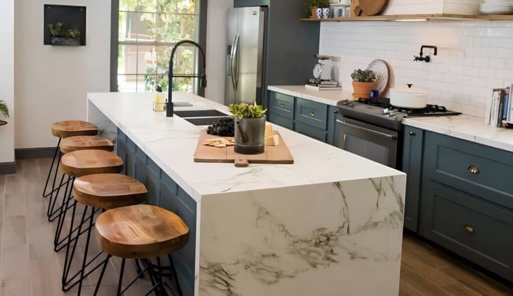 Kitchen with marble seated island and chairs, blue cabinets, and brown wood floors